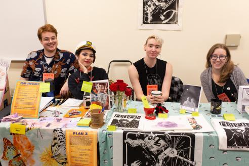 4 students behind a table selling their work at a comic book convention