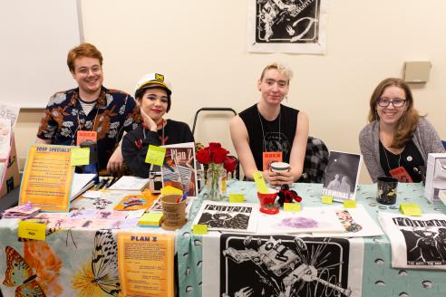 4 students behind a table selling their work at a comic book convention
