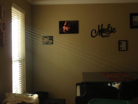 Rays of sunlight streaming from a window onto a black grand piano.