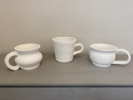 Three unfinished mugs made from stoneware clay.