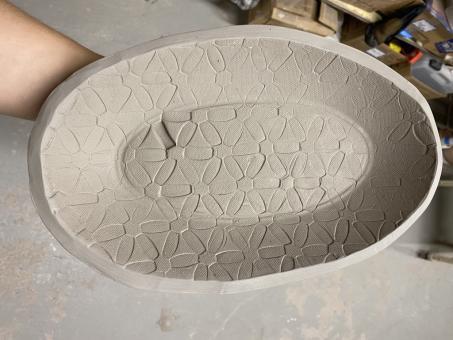 A hand built, buff stoneware clay tray with inlaid floral texture.