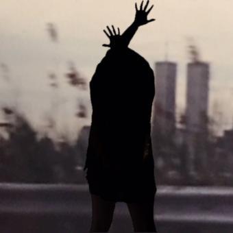 A silhouette of a person crossing their arms over their head, reaching their fingers out. The background is a blurry image of the twin towers and the New York City skyline.