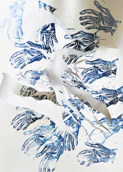 An image of repeating black and blue reductive prints of hands. The palms are facing up with lines showing the details of the hands. These hands are repeated all over the white paper with a design of swirls cut into the paper and removed so that portions of the hands are removed in a sculptural way.