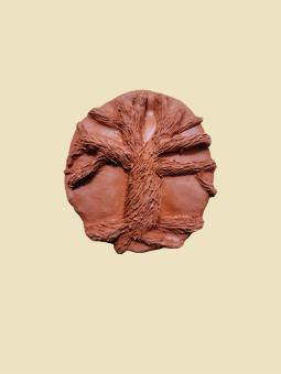 A brown piece of clay with a tree carved out of it showing a textured trunk. The tree has no leaves. 