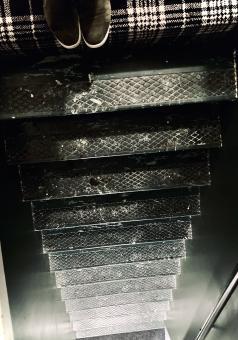 Photo of someone's shoes at the top stair, looking down a black staircase