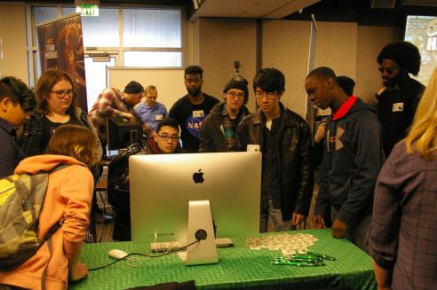 students gathered around a computer screen watching animation work by other peers