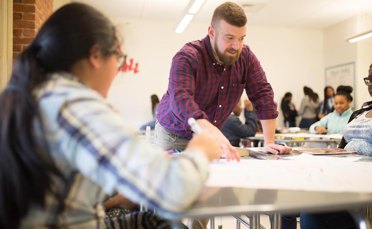 Alumnus Beau Morimando Teaching Students at a Desk