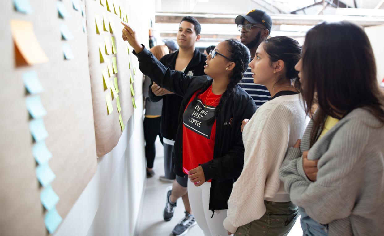 group of students looking at sticky notes on the wall