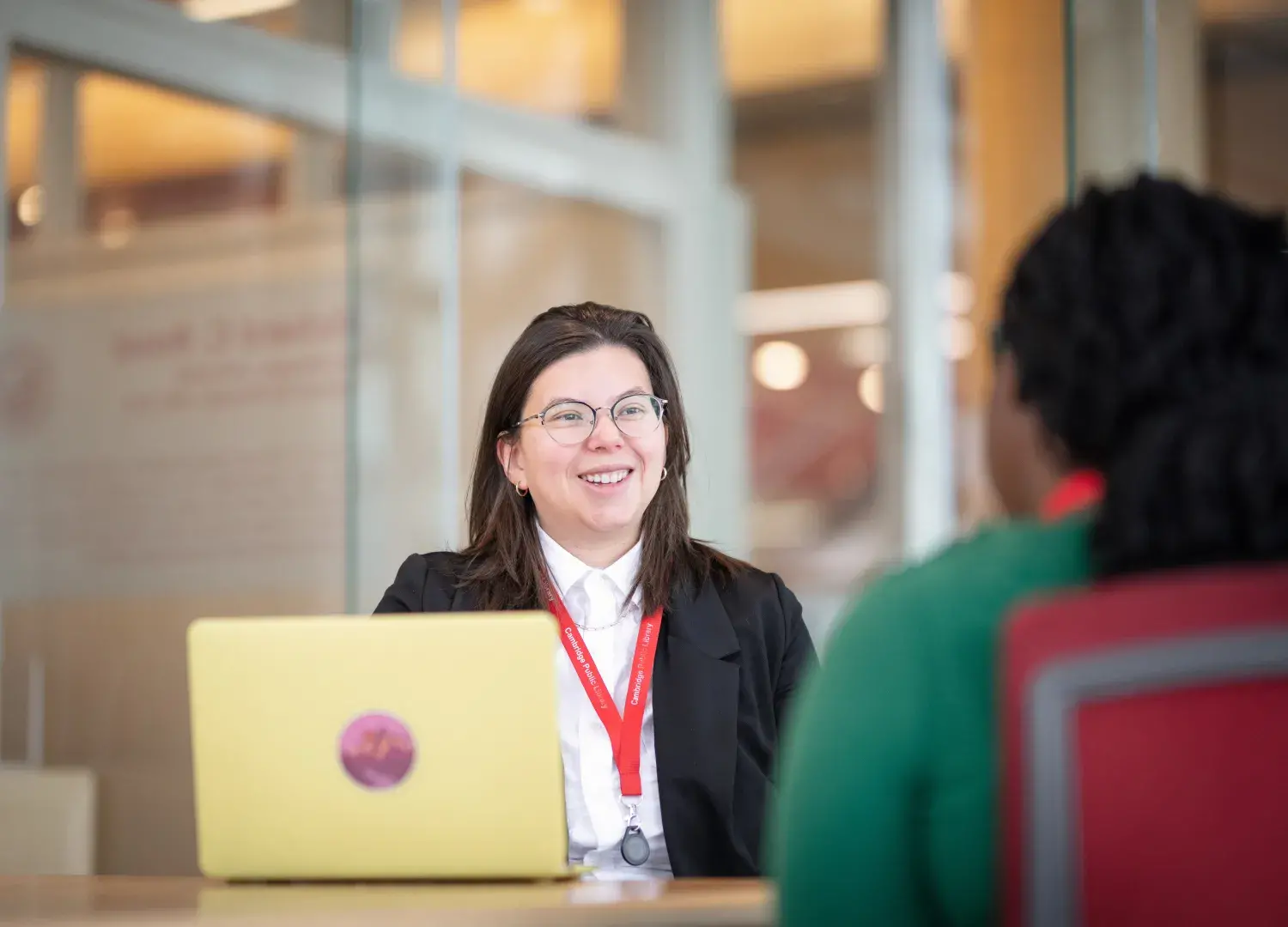 Emma Henson sitting at a table in the cambridge library speaking with a woman.