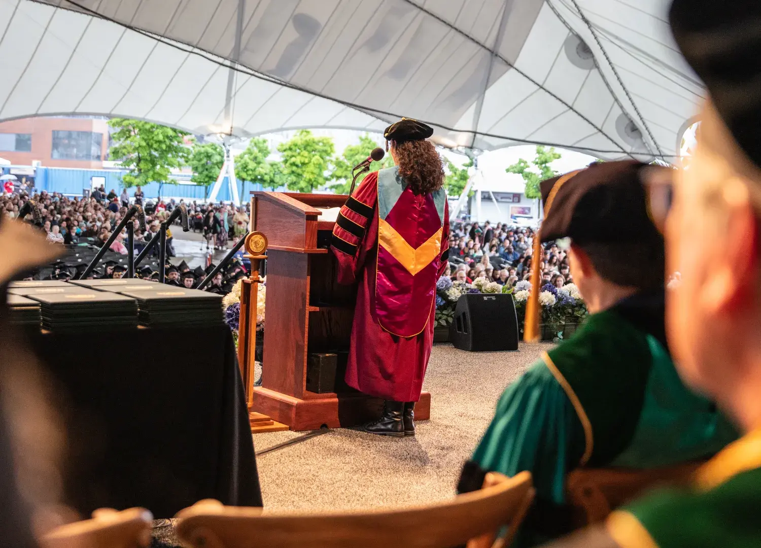 lisa fiore in academic regalia speaking for graduates in pavilion