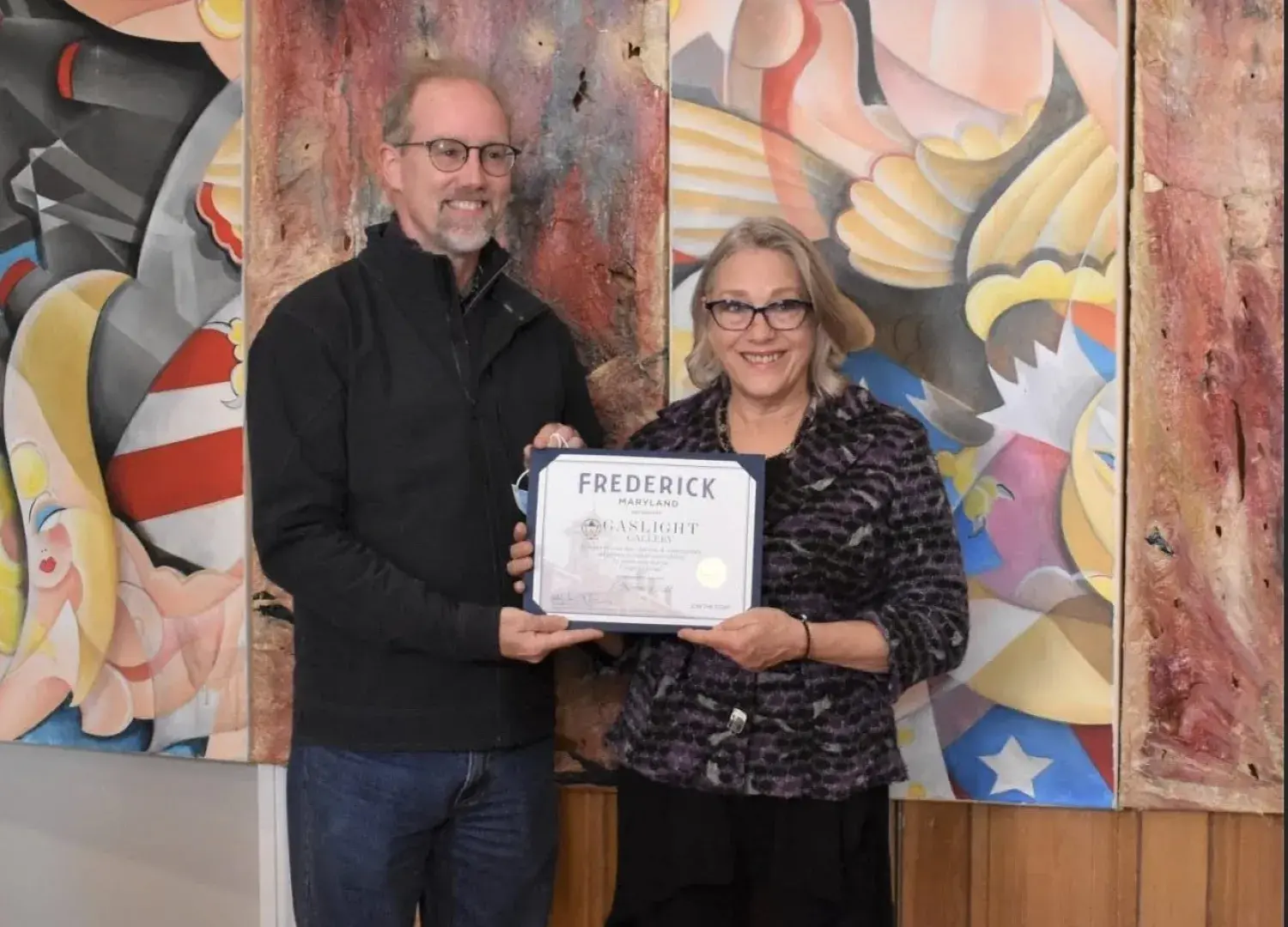 Michael O'Connor (left), the mayor of Frederick, Maryland, is pictured with Cynthia Scott during the ribbon-cutting event at Gaslight Gallery. Leigh Cortez's artwork is in the background.