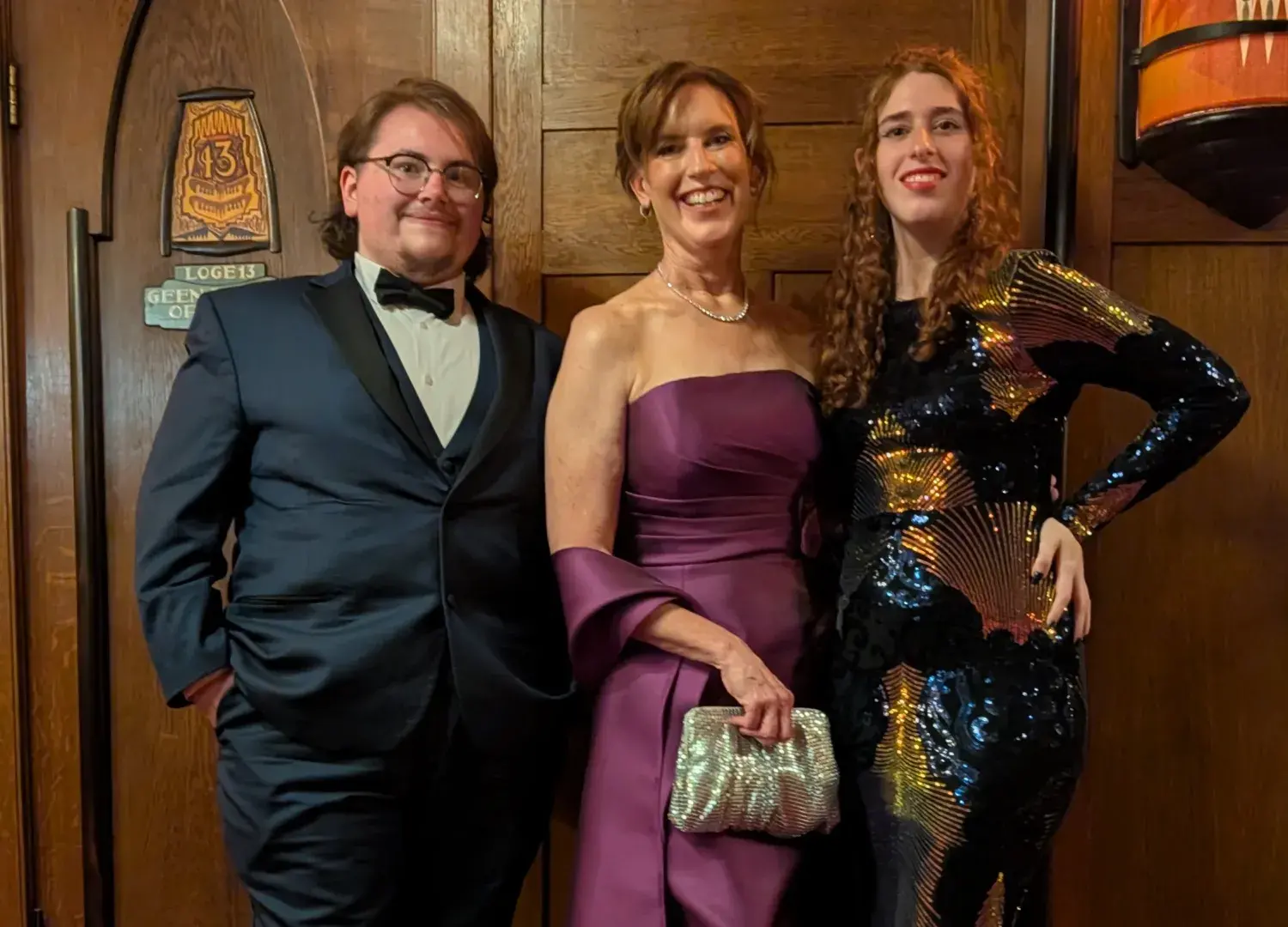 Catriona in magenta dress standing on red carpet with two other people, one in a black and gold dress and one in a black suit