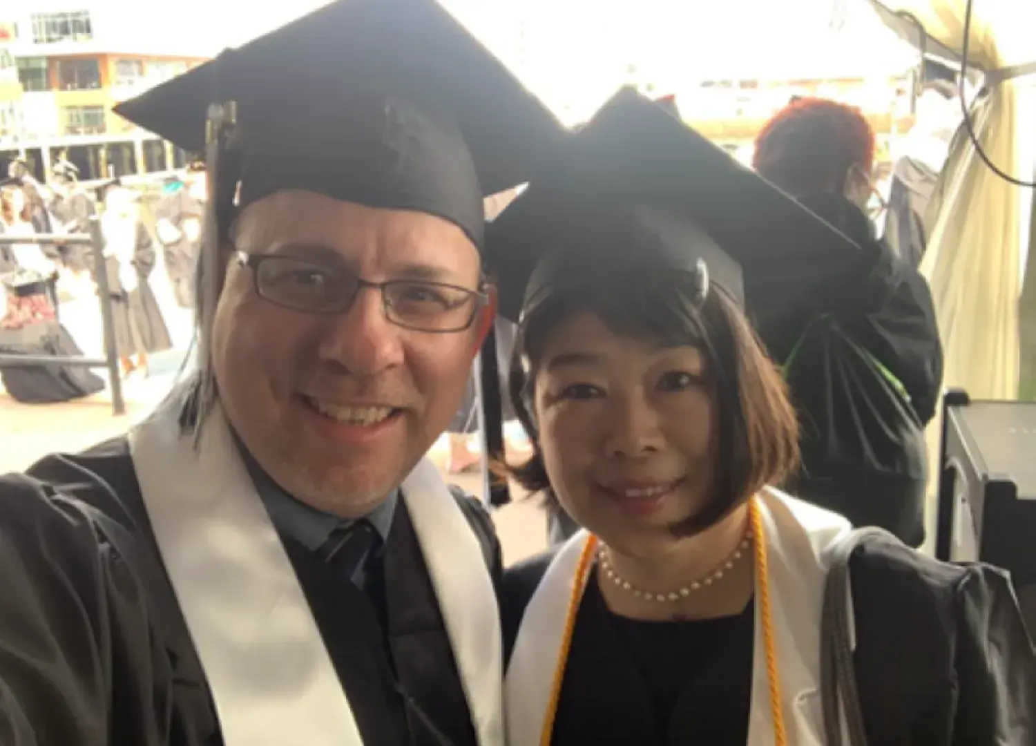Lesley graduates Hiroko and John Warford stand in their regalia