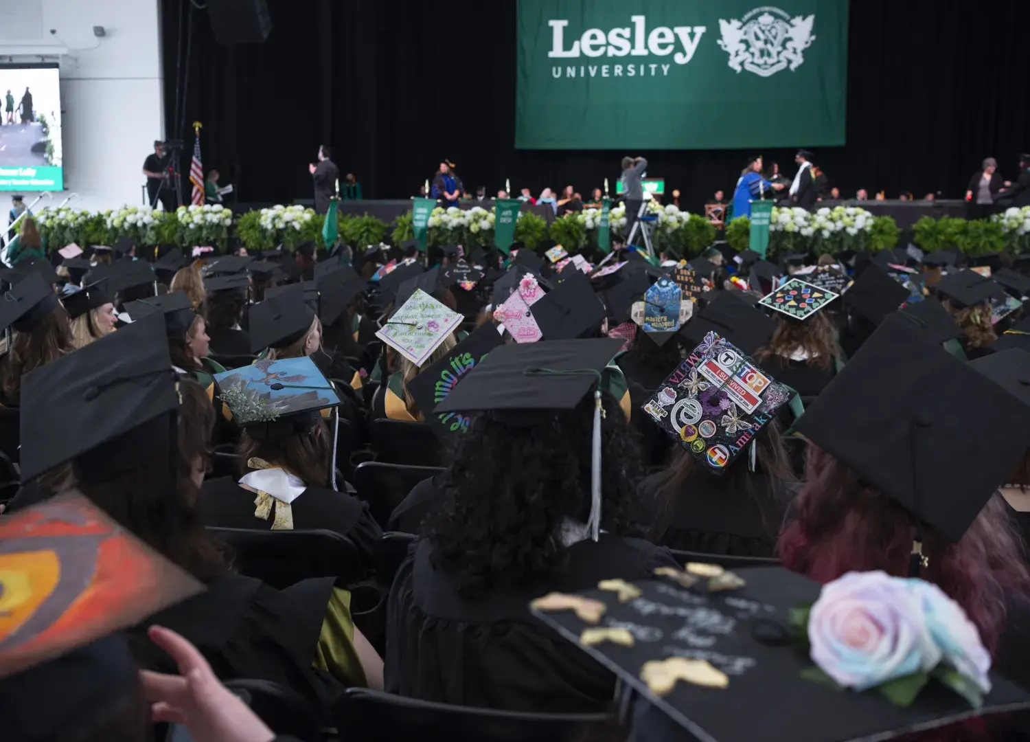 Graduates seated facing stage with Lesley banner
