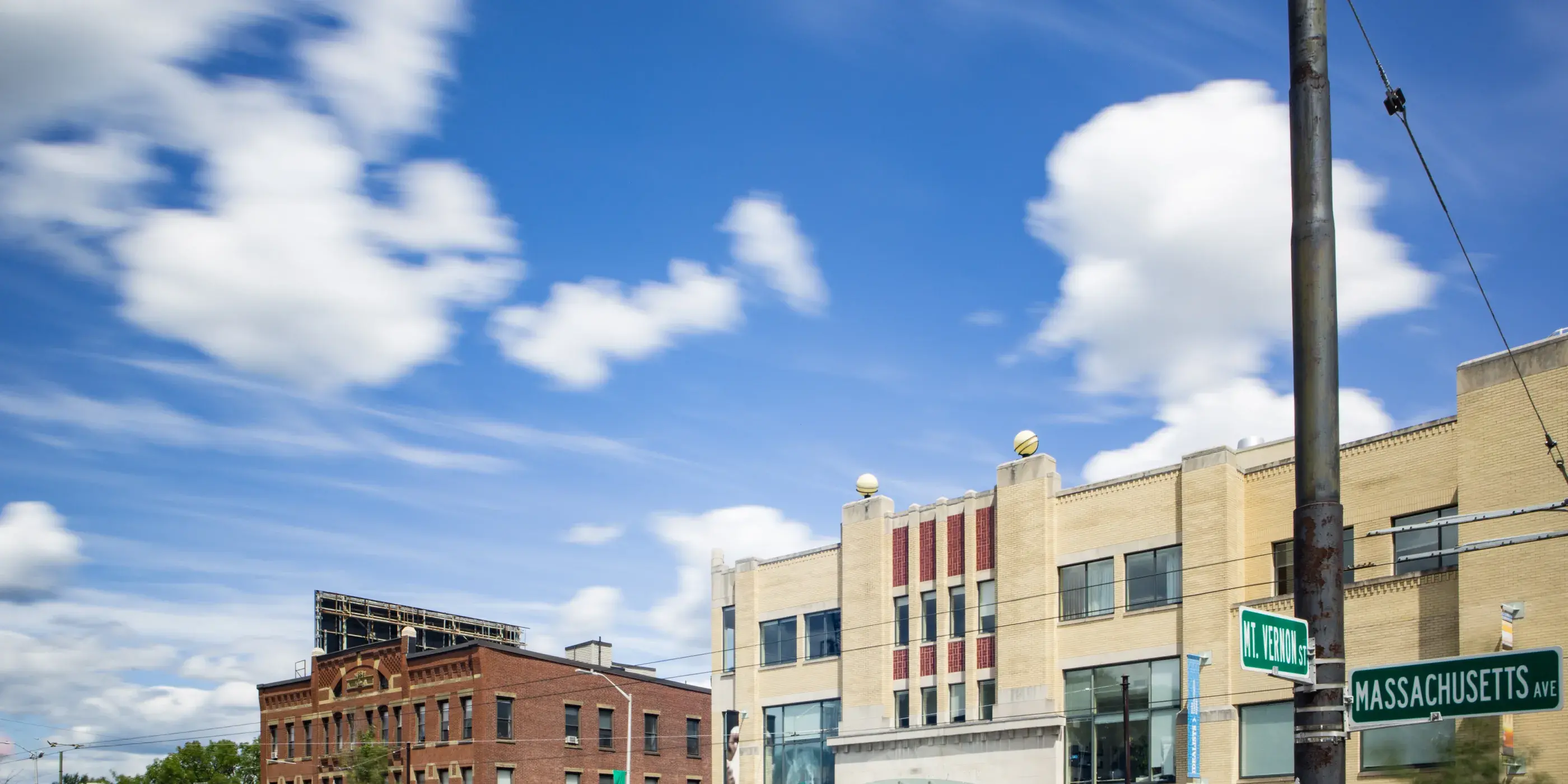 Buildings on a busy city street with blue sky and clouds
