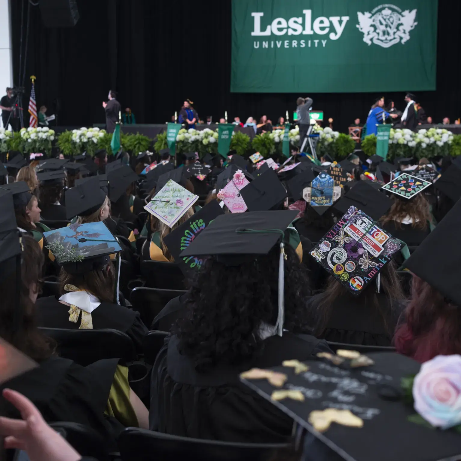 Graduates seated facing stage with Lesley banner