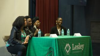 four people sitting at a Lesley University table, taking turns speaking into a microphone