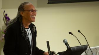 Arnetha Ball smiles as she leans into the podium in the University Hall Amphitheater.