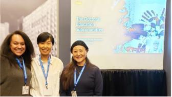 Three women standing in front of a display screen