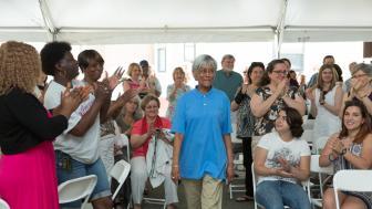 Ava Greene walks through a group of people clapping for her at an award ceremony.