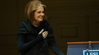 Gloria Steinem laying her hand across her chest in a gesture of gratitude