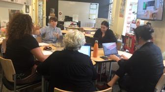 Lesley faculty members sitting around a round table in a classroom having a discussion.