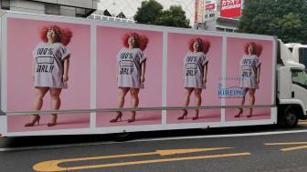 An advertisement on an 18-wheeler with a woman with red hair and a shirt that says 100% girl. Repeated four times on the truck.