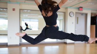A dancer leaps in a Lesley dance studio.