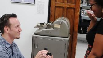 Man on one knee proposing with a jewelry box in hand