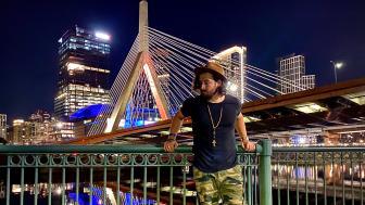 Devin Ferreira standing in front of the brightly lit Zakim Bridge in Boston