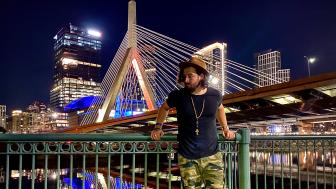 Devin Ferreira standing in front of the brightly lit Zakim Bridge in Boston
