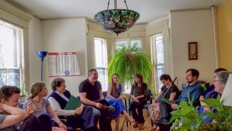 A group of peple sit in a circle in a room.
