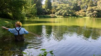 Maria Aliberti Lubertazzi wears waders and stands waist deep in a green pond.