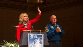Gabby Giffords waves and Mark Kelly clasps his hands on stage.