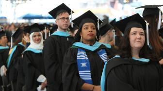 Graduate students stand at commencement