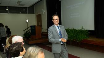 Hans Strauch in front of the audience, smiling, hands clasped