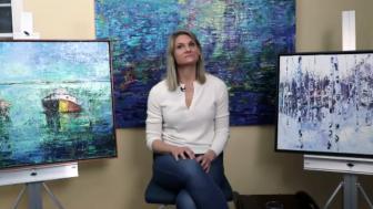 Julia Powell pictured in her studio surrounded by three paintings