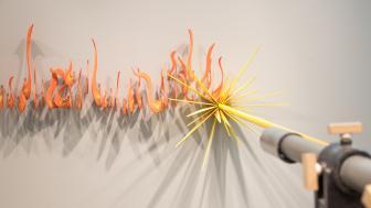A sculpture of a laser cutter emits fire.