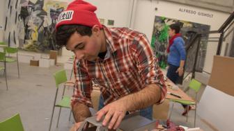A student works on a gray pickup truck made of cardboardin the bottom level of Lunder Arts Center.