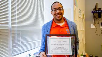 Kyair Butts holding his framed award.