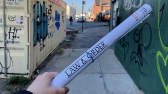 Outside, NYC, hand holding a rolled up paper printed with "Law & Order"