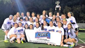 The women's soccer team holding the championship banner on the field. 