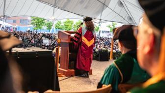 lisa fiore in academic regalia speaking for graduates in pavilion
