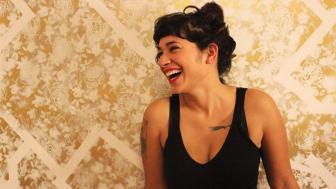 Melissa Lozada-Oliva laughing against a gold wall.