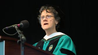 Molly Baldwin in cap and gown speaking at podium