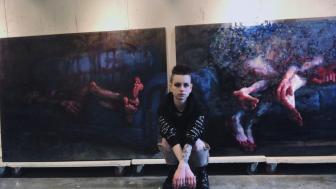 Moriah Faith in front of two of her paintings