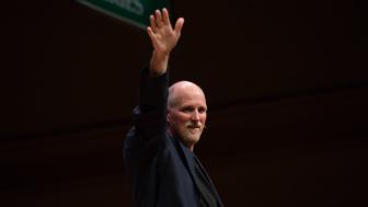 Paul Nicklen on stage, holding one hand up.