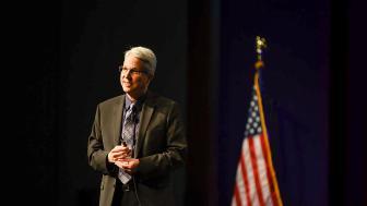 Peter Langman on a stage with flag in background