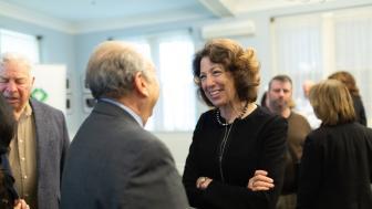 President Janet Steinmayer speaks to a man in a suit at the welcome reception