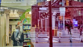 Image of a male Walgreen employee with a mask at work with the reflection of the street in the window